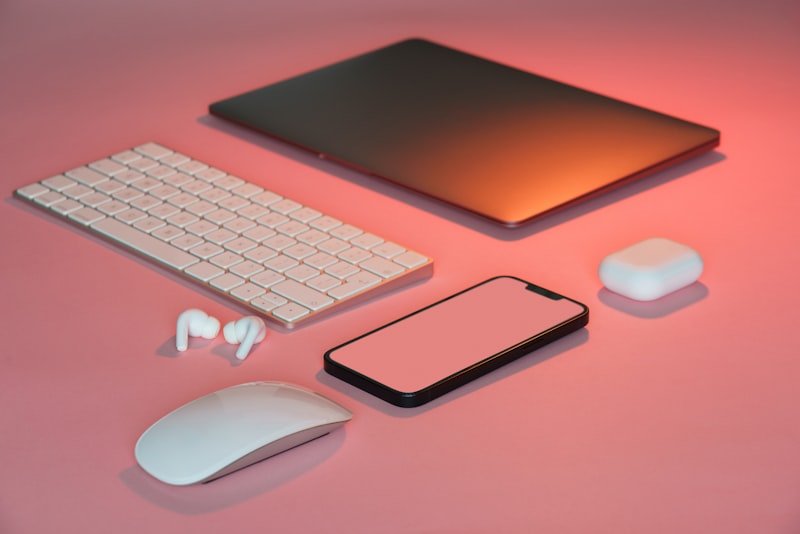 a computer mouse, keyboard, and other electronics on a pink surface